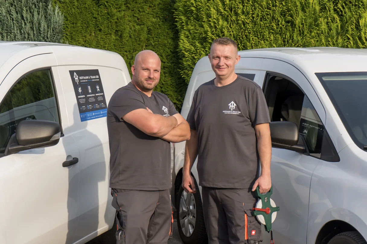 Marcell Hoffmann und Alexander Tramm vor ihren beschrifteten Firmenfahrzeugen